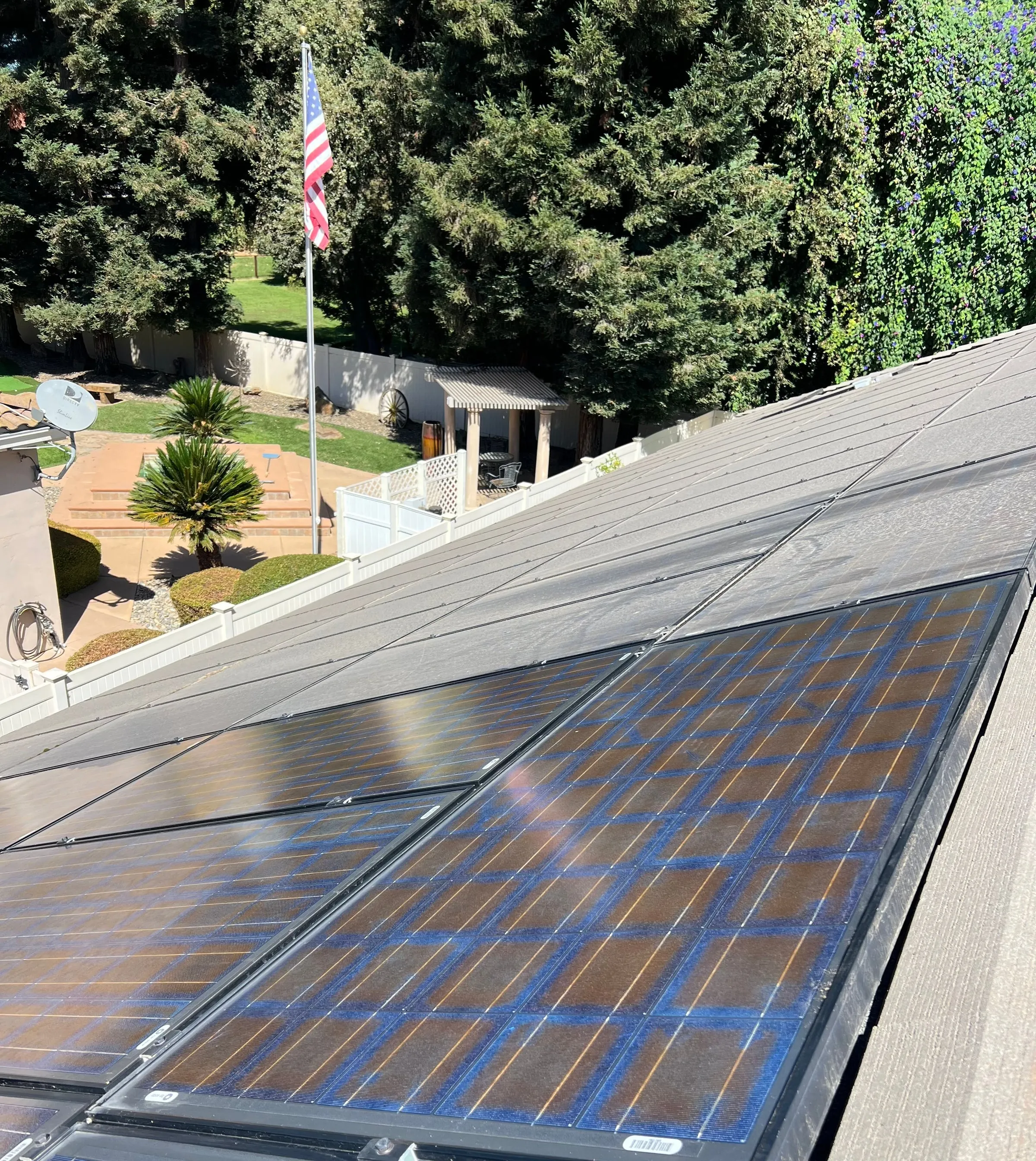 Residential roof-mounted solar panels overlooking a backyard